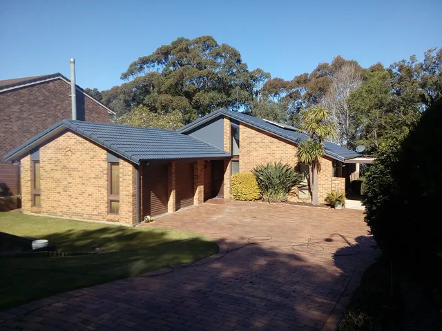 The same brick house with a clean dark charcoal tile roof after restoration.