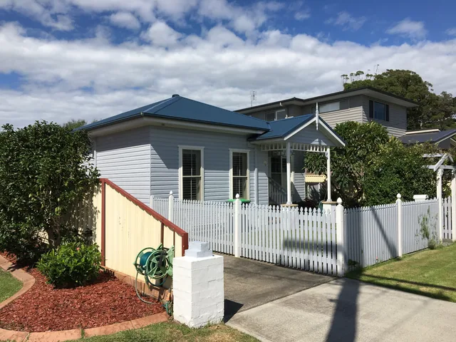 The same cottage with a deep navy metal roof after restoration.