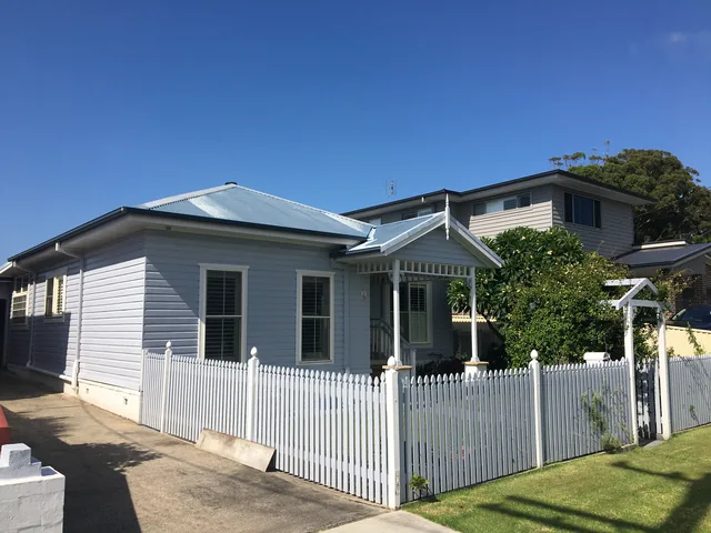 Weatherboard cottage with a faded light grey metal roof, before restoration.