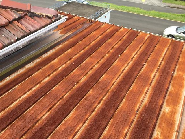 Corrugated metal roof with heavy rust across every sheet, before restoration.