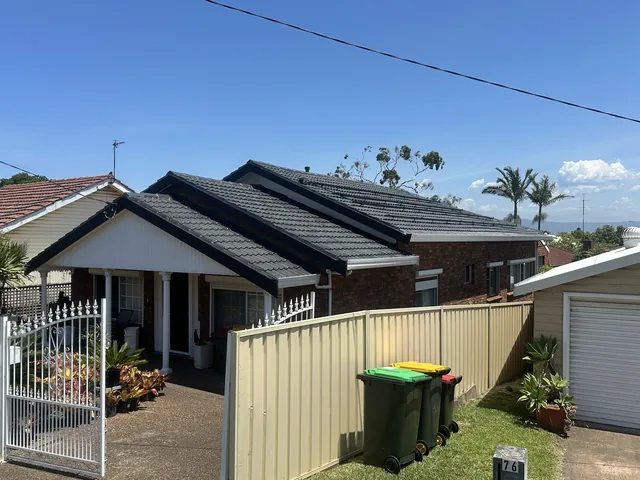 The same house with a dark charcoal tile roof after restoration.