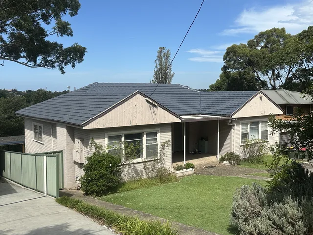 The same house with a dark charcoal tile roof after restoration.