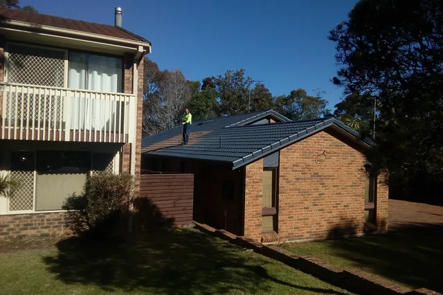Roofer standing on a charcoal tile roof during a job.