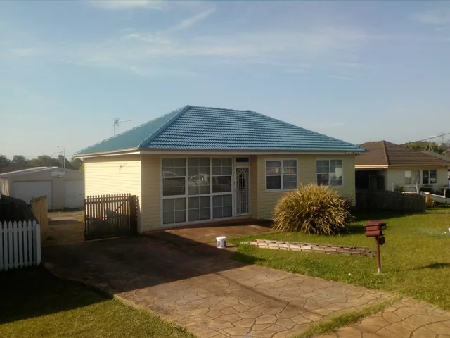 Single storey house with a restored blue tile hip roof.