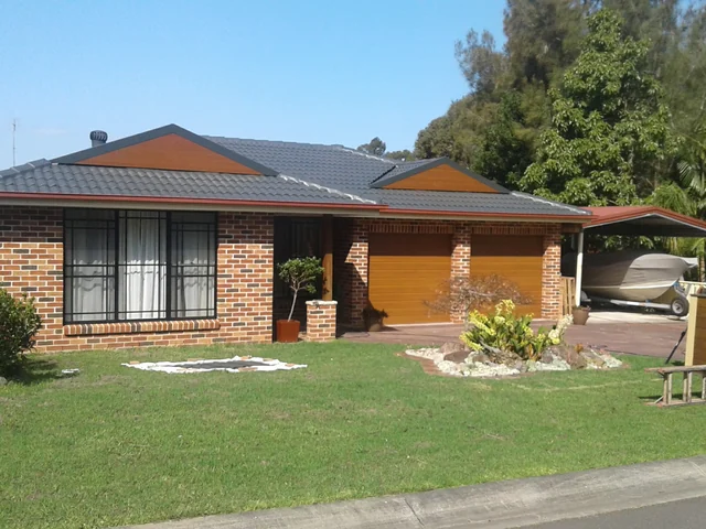 Brick veneer house with a restored charcoal tile roof, a garage door and a carport.