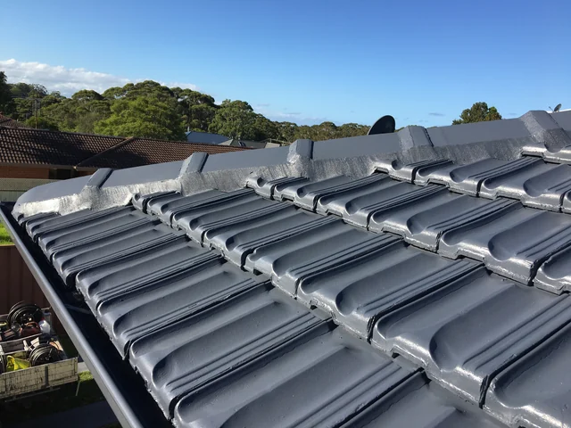 Restored charcoal tile roof with new ridge caps, close along the roof line.