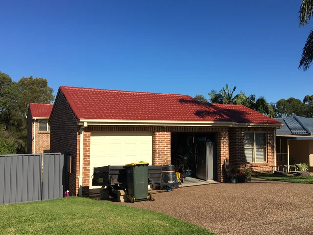 Brick veneer house with a freshly coated bright red tile roof.