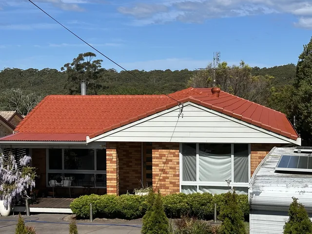Brick house close on a restored bright red tile roof.